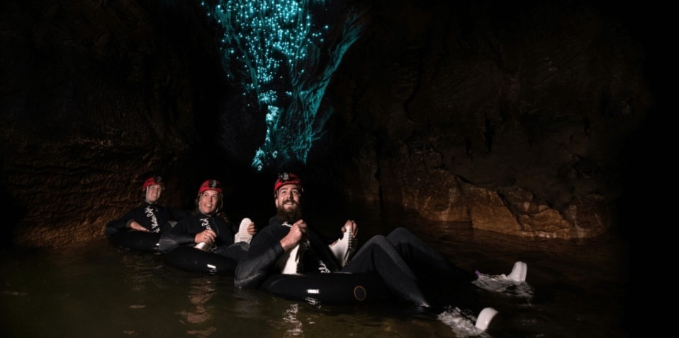 Group black water rafting in underground tunnels under glittering glowworms