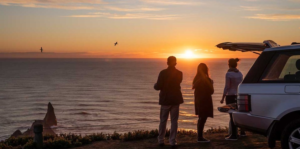 3 holiday makers watching the sunset  at Cape Kidnappers in Hawkes Bay