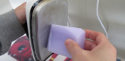 Push the wax up against the iron and let it drip onto the base, moving along the board to spread it evenly